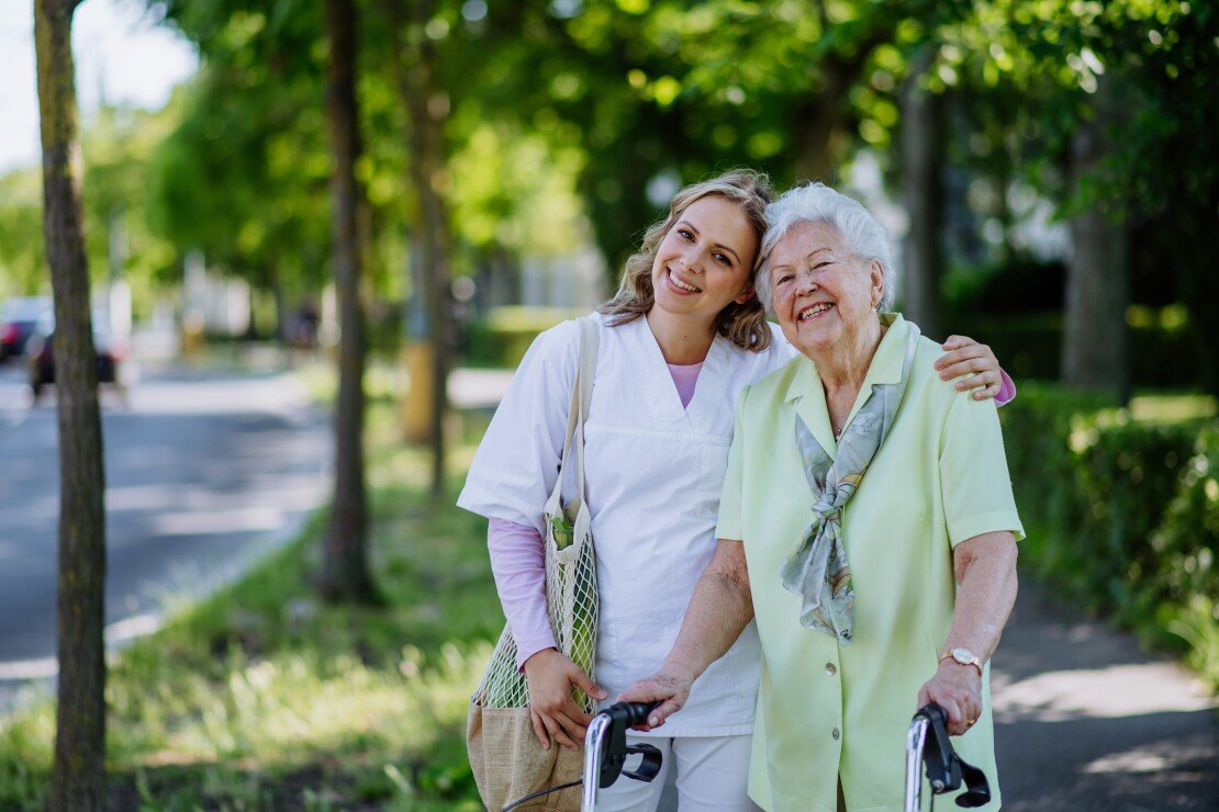 A caregiver and a senior enjoying a walk together outdoors